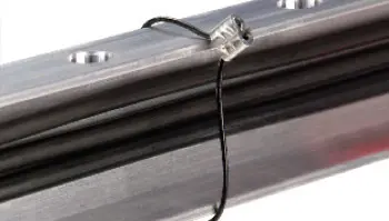 A close up of a metal rail with a Heyco Sunbundler Cable Tie 10" attached to it.