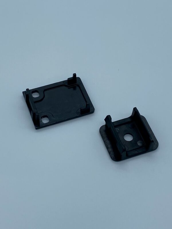 Two small black plastic components on white background.