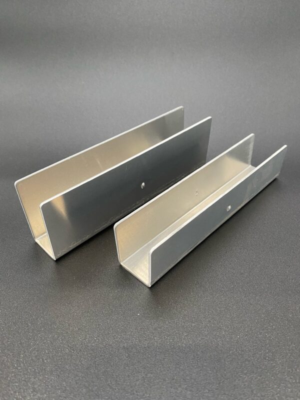 Two metal brackets on a dark surface.